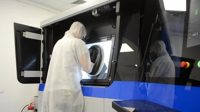 Person in white overalls works with machine with large rubber sleeves