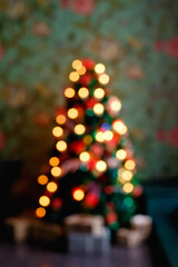 Abstract Christmas tree with bokeh decorations blurred background. The Christmas tree in lights is out of focus. Vertical frame.