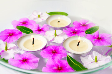 Obraz na płótnie Canvas Burning floating candles with pink flowers in a bowl of water, spa relaxation and meditation