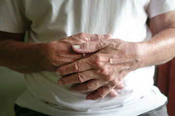 Close up view of senior man's hands clasped together.
