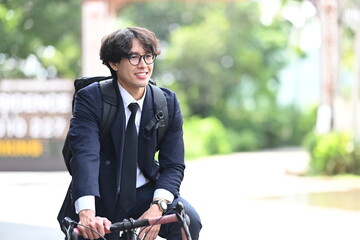 Smiling young businessman riding bicycle on on city street.