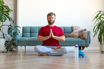 Yoga practice at home - middle aged man meditating while doing yoga. Full-length photo.