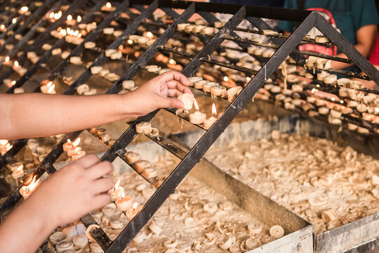 A female devotee places a prayer candles on a rack at a chapel. Shot at Baclaran church, Philippines.