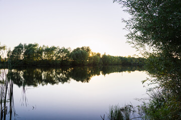 Fototapeta na wymiar Beautiful smooth lake in sunset lights. Selective focus. 