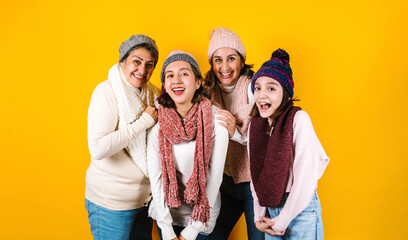 Winter portrait of happy latin family three generations of hispanic women on yellow background in...