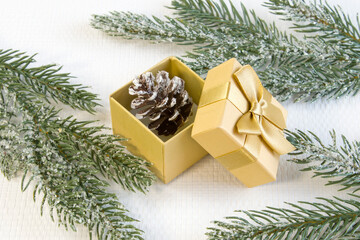 Naklejka na ściany i meble New year and Christmas concept of holiday decorations. Small decorative Christmas pine cone in golden gift box