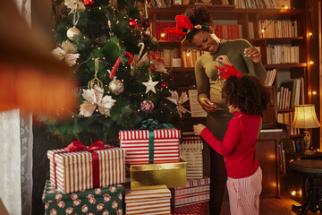 Obraz na płótnie Canvas Little helper with mother decorating Christmas tree