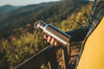 Man standing at viewpoint and holding thermos bottle