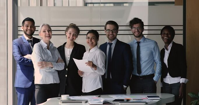 Seven multinational professional business team, diverse company members posing for camera, standing in modern office. Successful and ambitious corporate staff portrait. Unity, career growth concept