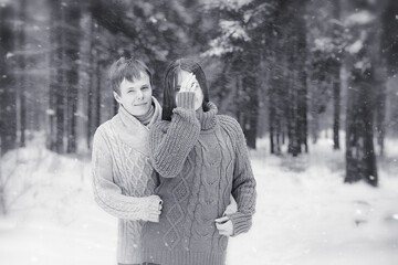 A loving couple on a winter walk. Man and woman on a date in the park in winter. Friends in a winter park