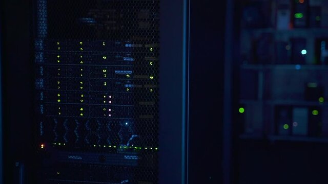 Closeup view of rack of working equipment and hardware in big data office spbas. Server shelves blink and work in dark database corridor without anyone. Complex infrastructure of render farm consists