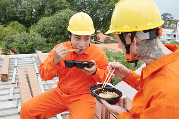Builders eating noodle soup at construction site for lunch and exchanging funny jokes
