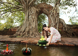 Young beautiful woman floating banana leaf basket call Krathong in Thai to pray respect to Goddess of water
