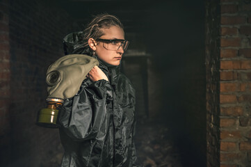 Fototapeta na wymiar Beautiful military girl. Portrait of a woman with a gas mask in a destroyed building. Post-apocalypse concept