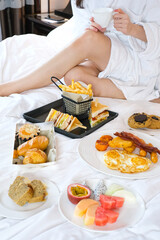 Obraz na płótnie Canvas Beautiful woman having breakfast in the hotel bed. Beautiful young Asian woman enjoy breakfast on bed in hotel bedroom. Woman holding cup of coffee, eating breakfast in bed in modern hotel.