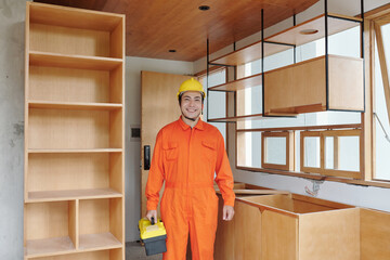 Happy Asian carpenter with toolbox standing in apartment he came to install kitchen counter