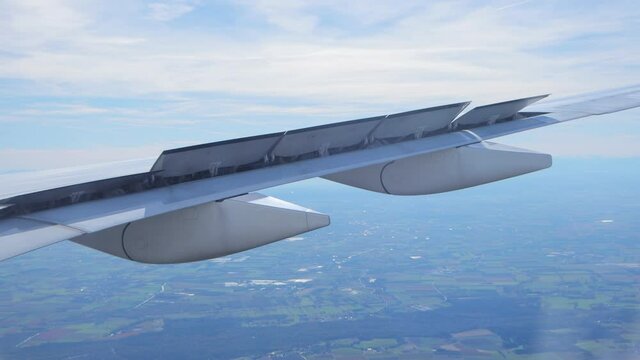 Plane spoilers lifted rraised up while plane flies in sky, decrease lift and and altitude and speed
