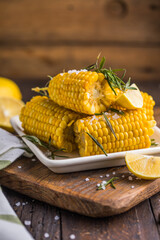 Delicious Mexican boiled corn cobs with sea salt   and lime serving board on black rustic...