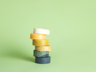 Six natural handmade round soaps in the form of the tower opposite the green background, in the...