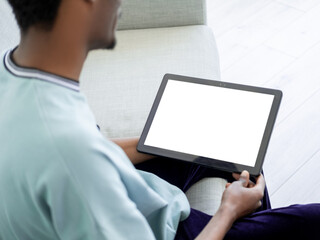 Blank screen. Video conference. Home rest. Casual unrecognizable man holding tablet computer sitting sofa in light room interior.