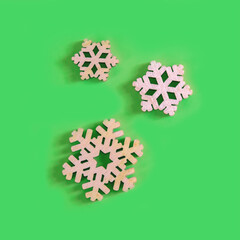 The above view on three handmade wooden snowflake on the green background, minimalism New Year or Christmas concept.