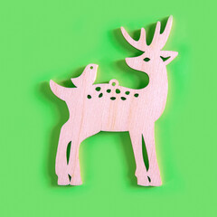 The handmade wooden deer with a bird on the light green background, minimalism New Year or Christmas concept.