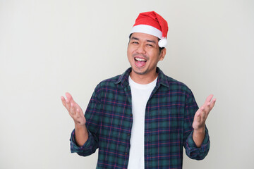 Adult Asian man wearing christmas hat with excited expression