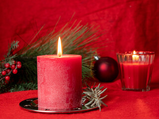 Red Christmas candle and Christmas decorations on a red background.