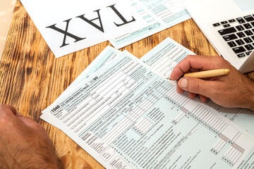 Naklejka premium two accountants fill in tax forms 1040 in two hands on a spacious table.