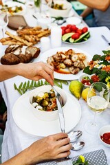 A festive family dinner or barbecue in the summer garden. Family leisure and celebration and food concept. People are eating at a garden party. BBQ, vegetables, wine and snacks. Life in the suburbs