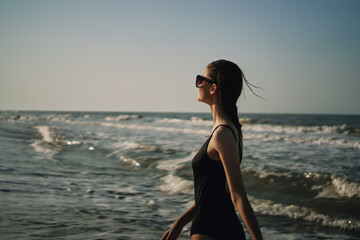 woman in black swimsuit walking on the beach ocean summer