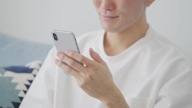 家でスマホを見る若い男性