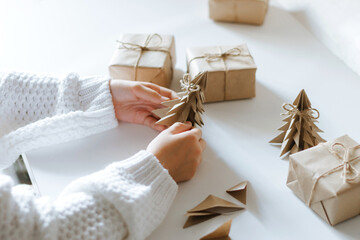 The child is preparing for Christmas, wrapping gifts, making an origami craft out of paper. DIY...