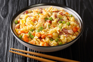 Traditional fried Chinese rice with vegetables, eggs, shrimps, pork close-up in a bowl on the...