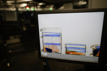 Shallow depth of field (selective focus) image with a screen showing luggages inside an x-ray scanning machine at an airport - airport security check.