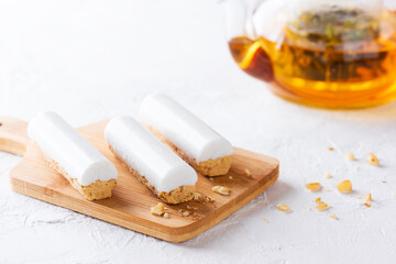 Raw carrot cake with coconut cream on a wooden board with a teapot. Sugar, gluten and lactose free, vegan.