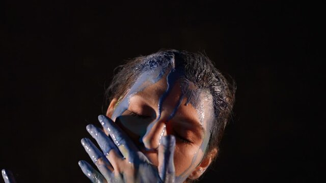 Close-up portrait of a woman in the dark improvisation of movement in multicolored paint