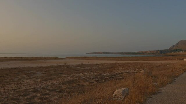 Beautiful sunset at Baia Santa Margherita at Monte Cofano Sicilian natural reserve seen from moving car, Italy. Panning slow-motion
