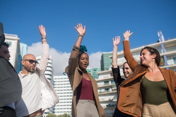 Happy business people putting their hands in air. Smart-dressed men and women of different nationalities during teambuilding process on terrace roof. Unity, teamwork, succsess concept