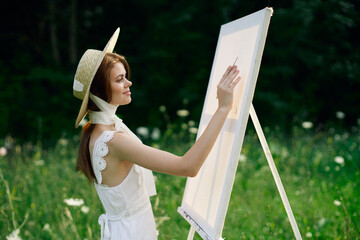 Woman in white dress in nature paints a picture of a landscape hobby