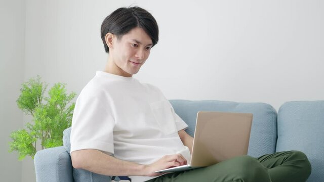 家でパソコンを使い仕事をする若い男性（ビジネスイメージ）