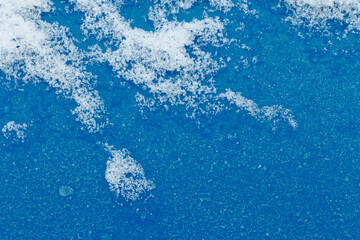 Ice crystals texture on a bright, blue plastic surface. Background. Outdoors.