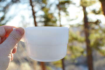 Cup in hand on the background of nature, defocused.