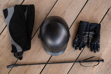 Black set of equipment for horse care and riding: helmet, whip, gloves, bridle, brushes on the...