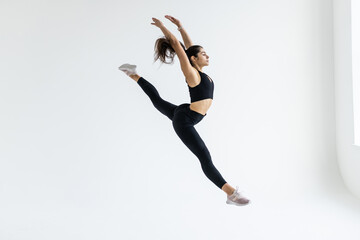 Fototapeta na wymiar Side view of a sporty young woman jumping on white background