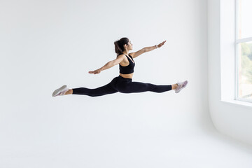 Side view of a sporty young woman jumping on white background