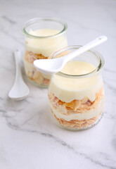 Napoleon cake with cream in small vintage jars on marble background.
