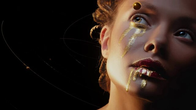The element of gold, the effect of a revived photo. Mysterious mystical heroine with golden drops on her face, golden tears, fantasy art. Portrait of a beautiful elegant woman in mystical art makeup