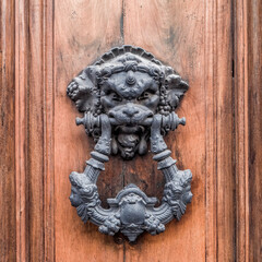 lion head door knocker on brown solid wood background
