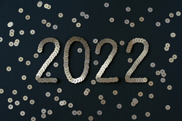 2022 embroidered with golden sequins on black textured background with scattered random sequins as...